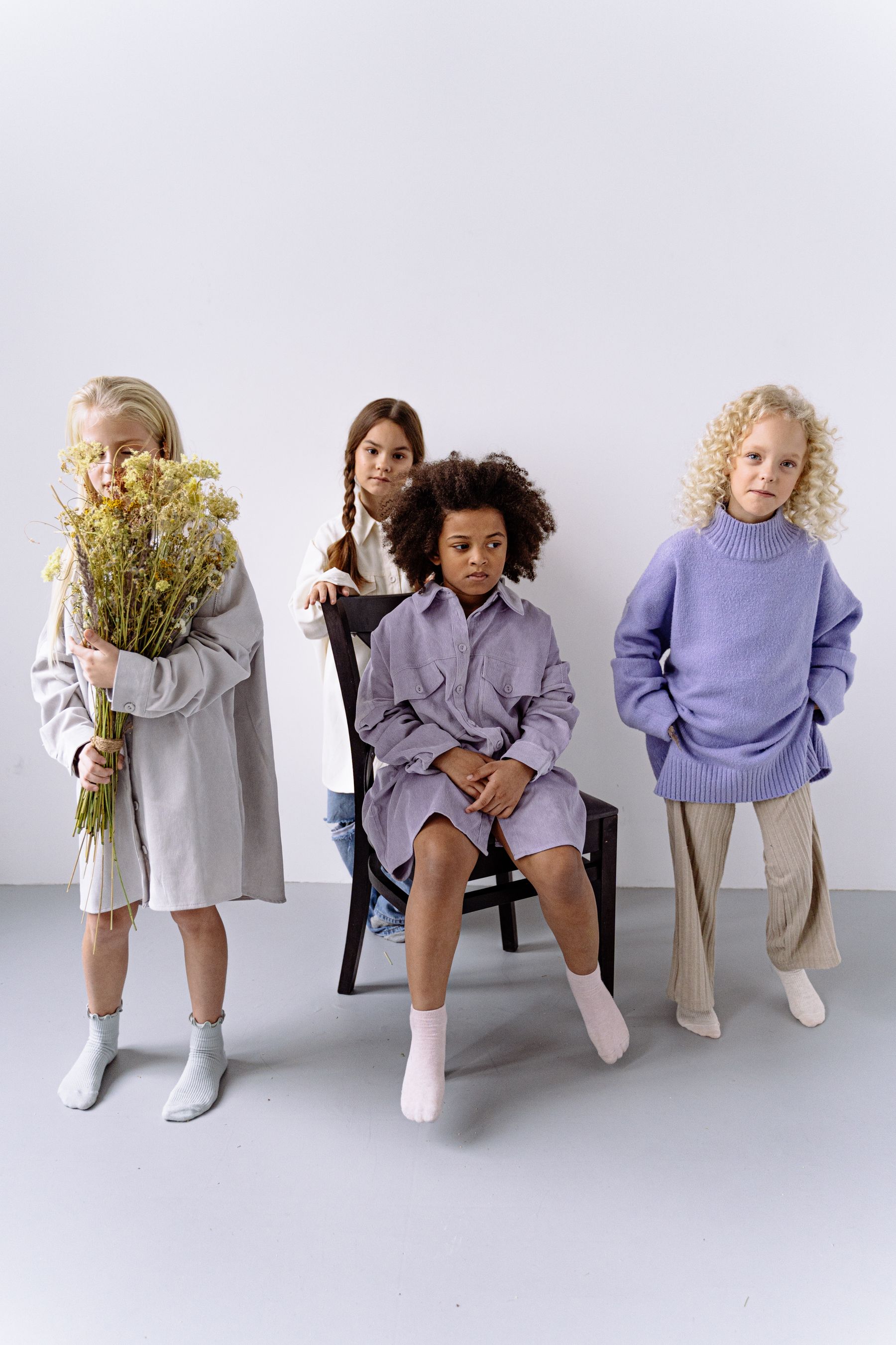 Four children wearing soft, colorful outfits in a studio